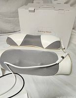 Full view of the white and gray Kaiming Meiya M3 massage pillow with power cable, positioned in front of its original white packaging box.