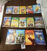 Fourteen DVDs laid out on a surface, displaying cover art for titles like Moana, Cars, Kung Fu Panda 2, Madagascar series, Ice Age, and Finding Nemo.