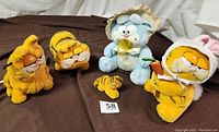 Full view of all five Garfield plush toys arranged on brown background showing variety of characters and sizes.