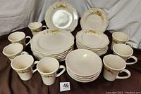 Full display of the 27-piece Plymouth Pfaltzgraff harvest pattern dinnerware set including plates and mugs arranged for view.