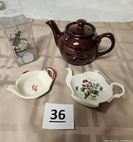 Photo showing Brown Betty teapot, two ceramic teabag holders, and boxed metal tea infuser with charm