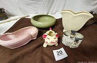 Five vintage ceramic planters and vases shown together including an oval bowl with father and son figure, pink speckled planter, green footed bowl, tulip vase, and pig planter.