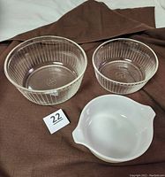 Two clear ribbed glass bowls and white Pyrex casserole dish shown together on brown cloth.