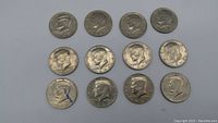 Top view of 12 JFK half dollar coins laid out on a flat surface showing obverse sides.