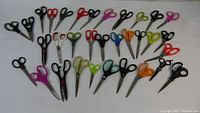 33 assorted scissors laid out on a white surface showing various styles, handle colors, and sizes.