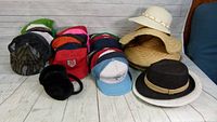 Full lot view showing multiple baseball caps, straw sun hats and a black and white sun hat.