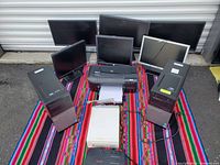 Full view of lot on colorful fabric showing Dell desktop towers, six monitors, HP printer, and UPS units