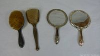 Front view of two hair brushes and two hand mirrors.