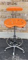 Front view of orange tractor-style seat and backrest with chrome base and footrest