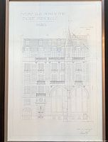 Framed architectural blueprint displaying the front facade of the building with title text on top.