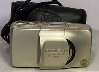 Front view of closed camera showing sliding lens cover and case in background