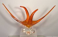 Front view of vintage Chalet art glass bowl with amber elongated curved arms stretching out from clear glass base.