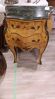 Front view of burl wood bombé cabinet showing three drawers and marble top