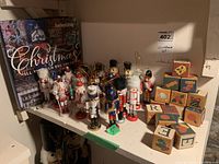 Mini nutcracker ornaments together with painted wooden blocks and Southern Living Christmas book on shelf.