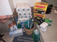 Full view of the cleaning supplies including paper towels, garbage bags box, toilet paper rolls, dishwashing liquid, cat litter box, and more.