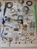 Overview photo showing the entire collection of costume jewellery pieces spread on a white surface, including necklaces, bracelets, earrings, and brooches.