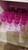 More than a dozen pink wine glasses placed on shelf, showing quantity and general appearance
