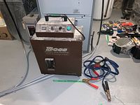 Full front view of the Boss Hydroxyl Odor Processor with jumper cables next to it on the floor.