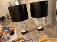 Pair of ceramic base nautical lamps with black cylindrical shades viewed side by side on the floor