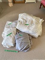 Photo showing the complete set of folded bedding items on carpeted floor with labels indicating each piece of the queen bedding set.