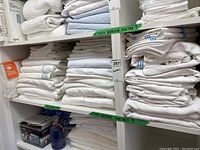 Multiple stacks of folded white king-size linens on shelving
