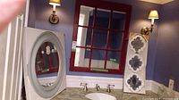 Red framed grid style mirror, white paddle-shaped frame mirror with three small shaped mirrors, and small white framed square mirror in a room with blue walls and sconces.