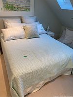 Full view of queen size bed with bedding and pillows arranged