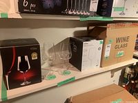 Shelf with various boxes of wine glasses including two Trudeau Bohemia boxed sets and individual glasses displayed