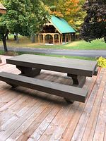 Full side view of the stained log picnic table and bench set on a wood deck