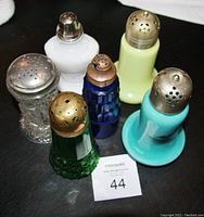 Six antique sugar shakers in various colors and styles grouped to show variety of body and tops