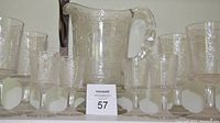 Full set view showing one large pitcher, four wine glasses, and four cordial glasses arranged together on a flat surface.
