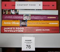 Photo of the spines of five Jamie Oliver cookbooks stacked horizontally showing titles and condition.