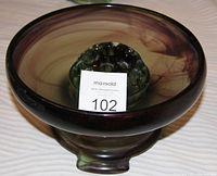 Top-down view of the large bowl with green frog flower holder inside, showing the satin finish inside and polished outside with rich purple-green swirling tones.