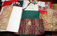 Photo of folded Christmas-themed tablecloths, runners, and napkins in various colors and patterns on a wooden surface.