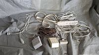 Five extension cords and power strips laid out on a gray surface, shows various plugs and outlet configurations