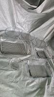 Image showing a set of three round glass bowls and four rectangular glass casserole dishes placed on a white cloth background.