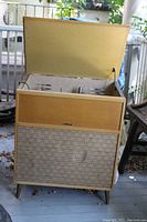 Photo of closed wooden Hi Fi console with woven fabric speaker panel and wood trim.