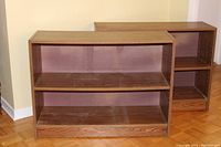 Photo showing two wooden book shelves side by side, with adjustable middle shelves and a medium oak finish.