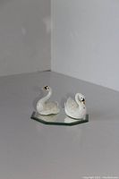 Pair of white ceramic swan salt and pepper shakers on octagonal mirrored glass base, shown from a slight angle on a white surface.