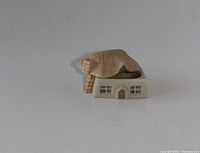 Front angled view of a tiny box shaped like a thatched cottage with detailed windows and door