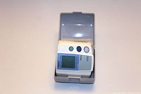 Omron wrist blood pressure monitor with digital screen and cuff in plastic storage case, shown from front