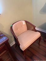 View of cane sided chair with beige fabric seat and back, dark wood frame with curved arms and legs.