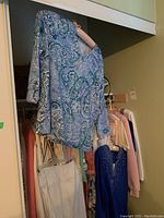 Blue paisley long sleeve shirt in closet with other clothing visible