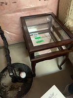 Display table angled shot showing the wooden frame, glass top, and mirrored shelf beneath.