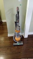 Front view of upright vacuum showing main body, wand, hose, and power cord