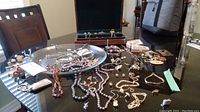 Wide view of assorted jewelry pieces on black surface with wooden jewelry box in background