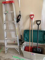 Overall lot showing 6-foot Featherlite ladder, electric weed trimmer, snow shovels in tote, and storage bin.