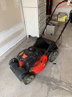 Full view of red and black Craftsman lawn mower showing grass catcher bag and wheels.