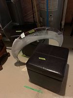 Two stools and two mirrors arranged near a water heater. One stool is a square ottoman style, the other is a rectangular stool with legs. The two mirrors are different shapes and sizes.