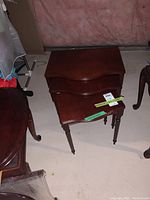 Three stacked wooden nesting tables in reddish-brown finish with turned legs, viewed from above.